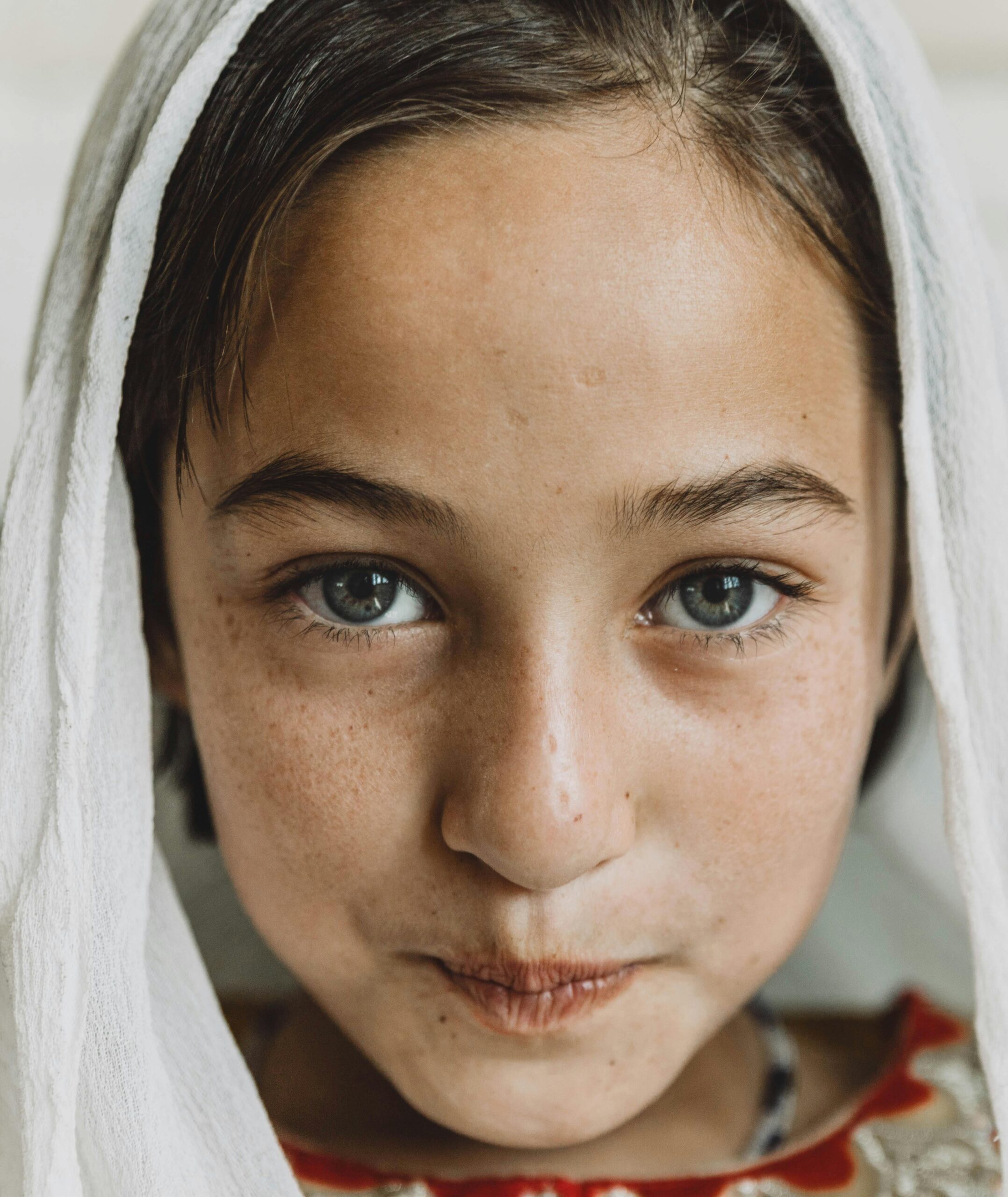 Charming portrait of a young girl with a headscarf, showcasing natural beauty and innocence.